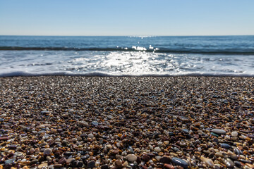 Sparkling waves on the beach hits the pebble beach in Antalya Turkey, Holiday and Travel concept, sunny and blue sky, nobody, no people, space for text, selective focus.