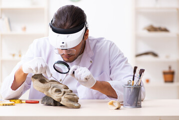 Young male archaeologist studying ancient african stonemask