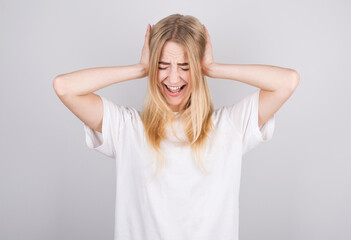 Annoyed woman sticking plug fingers in ears not listening to loud noise sound isolated on white...