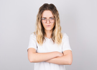 Fototapeta premium Photo of angry grumpy young caucasian female dressed casually keeping arms folded, looking at camera with strict and skeptical expression