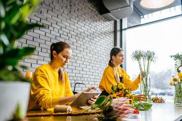 Creative millennial female designer sit at desk in modern shop interior and make order for next...