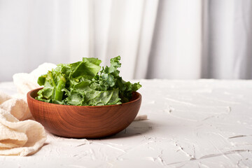 Healthy food concept, fresh organic kale in wooden bowl on the white table background with copy space