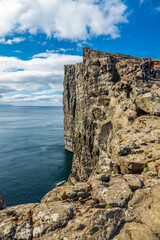 Unrecognizable tourists taking photos on top of the steep coastline