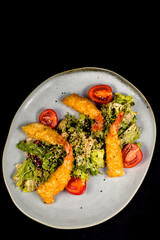 Salad with chicken fillet, lettuce and vegetables on a black background