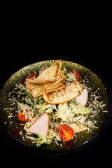 Salad with chicken fillet, lettuce and vegetables on a black background