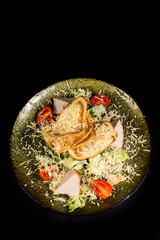 Salad with chicken fillet, lettuce and vegetables on a black background