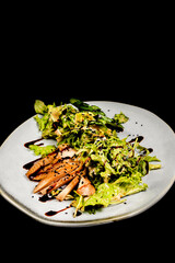 Salad with chicken fillet, lettuce and vegetables on a black background