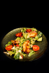 Salad with chicken fillet, lettuce and vegetables on a black background