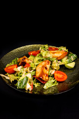 Salad with chicken fillet, lettuce and vegetables on a black background