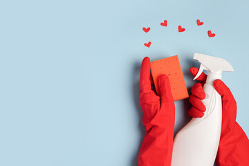 Female hand with cleaning products and red hearts on blue background. Cleaning or housekeeping with love. Copy space. Flat lay, Top view.