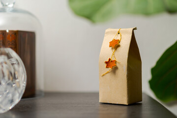 Selfmade gift box out of old beverage carton decorated with star shaped cut out dried roange peel standing on black wooden shelf