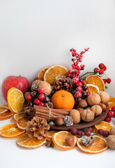 Obraz na płótnie Canvas Christmas decor with nuts, cinnamon, cones, berries, orange citrus. Christmas and new year festive concept. traditional winter holiday composition with nature decor.