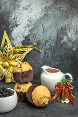 Vertical view of new year mood with delicious freshly baked small cupcakes chocolate and black radish next to golden bell and accessory on dark background