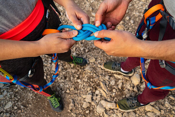Hands of a couple of climbers making the eight knot in her harness to start climbing. Working as a team and in love © Maria