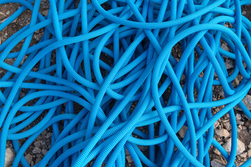 Blue rock climbing rope lying on the ground made of stones made a mess