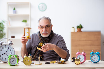 Old male watchmaker working in the workshop