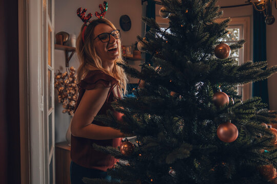Attractive smiling woman decorating Christmas tree. Christmas and New Year concept.