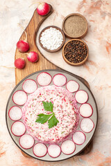 Vertical view of delicious chicken salad with beet on a gray plate red radishes on wooden cutting board and different spices on mixed color background