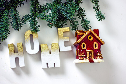 Home Sweet Home Flat Lay. Decorative Red House With Candlestick Windows And Beautiful Wooden Letters With Gold Plated Inscription Home On The Background Of A Spruce Branch, Bokeh Effect, Copy Space