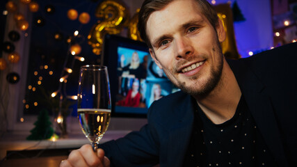 Celebrating Virtual Christmas New Year's Eve party 2021 at home during Covid-19 pandemic. Man holding and toasting champagne glasse How to celebrate and decorate foiled balloons of 2021.	