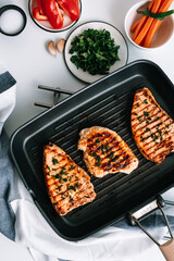 Grilled turkey steak with herbs and spices in black grill pan on the table.