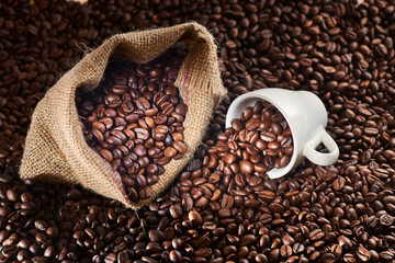 Studio Shot of White Cup of Coffee and Burlap Bag of Coffee over coffee beans
