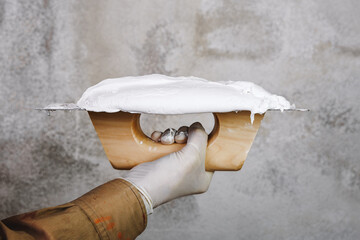Hand of construction worker with trowel and plaster. Plasterer is ready to repair a weathered wall. 
