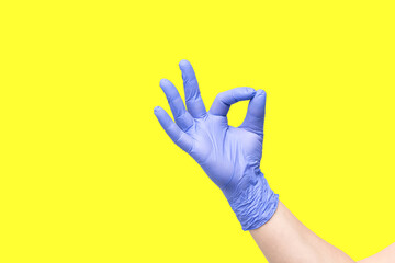 Hand in glove isolated on yellow background. Symbol OK. Everything is good. All right. Okey. Okay. Very good. A little bit. You're right. You are the best. Victory over the disease. Found a solution