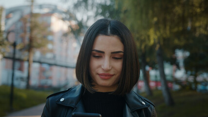 Young unhappy pretty woman wearing a leather jacket is dealing with the phone.