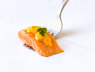 Salmon fillet on a fork with herbs and hollandaise sauce. Isolated on white background