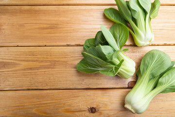 Fresh green bok choy or pac choi chinese cabbage on a brown wooden background. Top view, copy space.