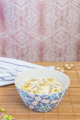 A vertical shot of a healthy breakfast of a bowl with yogurt, seeds, fruits and nuts