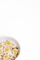 A vertical shot of a healthy breakfast of a bowl with yogurt, seeds and fruits on a white background