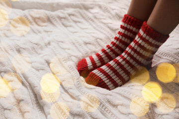 Woman in warm socks on knitted blanket, closeup. Space for text