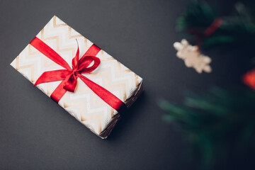 Christmas and New year gift box wrapped in festive paper and decorated with red ribbon with bow on...