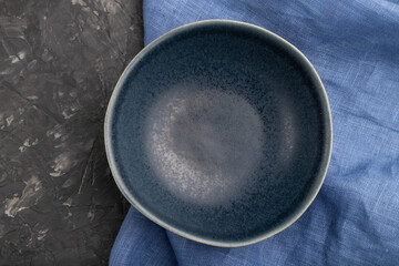 Empty blue ceramic bowl on black concrete background. Top view, close up.