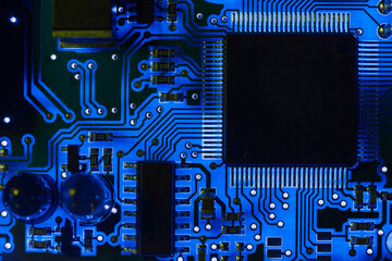 Close-up of a modern blue printed circuit board (PCB) with stripes of conductors between a...