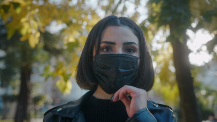 Young woman on the street during pandemic period and she is taking off her black mask and while...