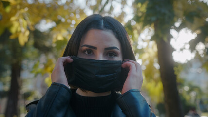 Young woman on the street during pandemic period and she is taking off her black mask and while...