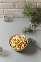 Olivier salad russian in a bowl on a gray background. Traditional and festive Russian cuisine. Copy space. Vertical orientation.
