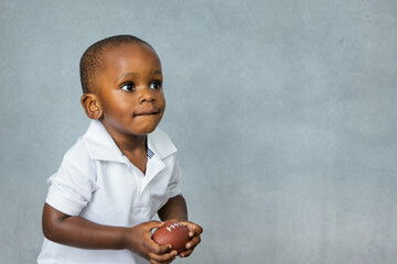 Cute toddler preschool age little boy playing with a football toy