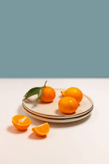 Fresh tangerine or clementin fruits on a beige plate with a gold rim on the table. Colorful fruit background. Decorative christmas holiday composition