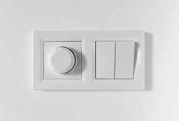 Pair of simple light switches with dimmer. Inexpensive plastic mechanical double switch with thermostat against white wall. Old air conditioner control panel. Smart Home Climate Control Appliances