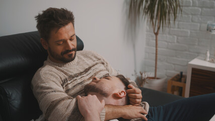 Lovers relaxing together on the couch. Handsome man resting his head on the lap of his husband....