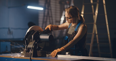 Female worker working with metal cutting saw