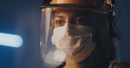 Fototapeta premium Exhausted female worker in hardhat removing medical mask