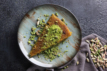Oriental sweets. Pahlava with nuts, pistachio in a large dish on a black table. Turkish dessert. Background image, copy space, horizontal, top view, flatlay