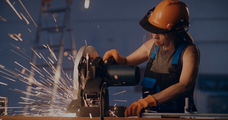 Female worker working with metal cutting saw