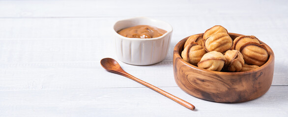  baked nuts with  boiled milk in a wooden  bowl  and caramel on a white table