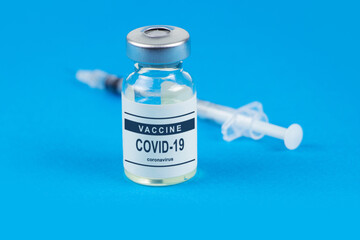 Vaccination. Syringe and vaccine COVID-19. Coronavirus on blue background